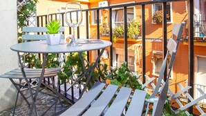 Un balcón con una mesa, sillas y una planta en maceta.