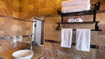 Un baño con pared de mármol, un lavamanos y un perchero con toallas.