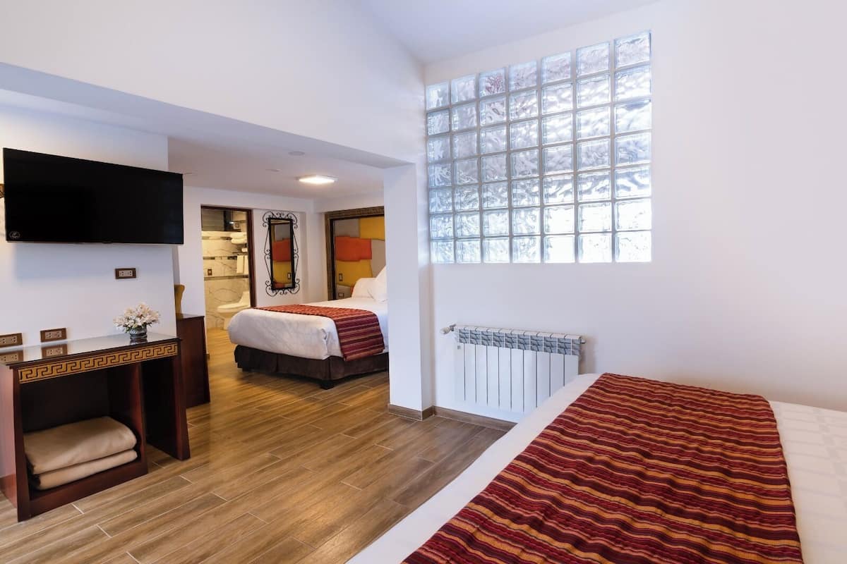 A hotel room with a bed, a desk, a TV, a window, and a bathroom.
