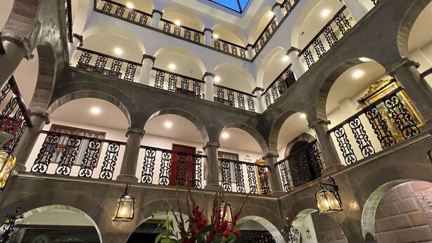 Ein Hotelinnenraum mit einem zentralen Atrium, mehreren Balkonen mit schmiedeeisernen Geländern und einem Oberlicht.