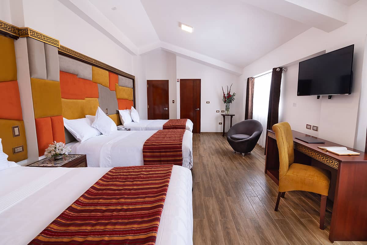 A hotel room with two beds, a desk, a chair, and a TV.
