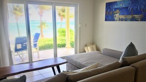 Una sala de estar con un sofá, una mesa y vista al océano a través de un ventanal corredera.