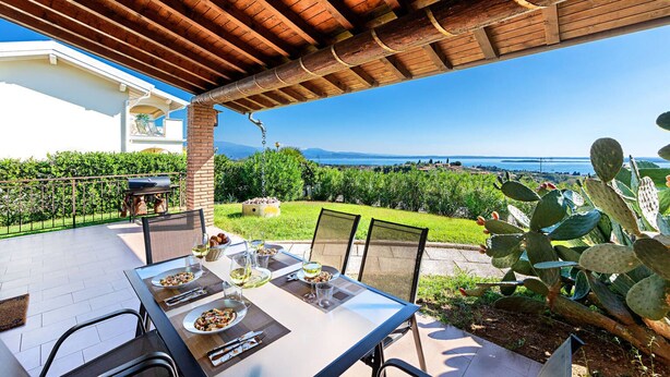 A patio with a table set for dining, overlooking a garden with cacti and a view of the sea. - Fantastic Villa in Soiano del Lago  for 6 people with pool  (Soiano del Lago)