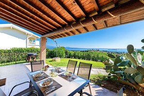 A patio with a table set for dining, overlooking a garden with cacti and a view of the sea. - Fantastic Villa in Soiano del Lago for 6 people with pool (Soiano del Lago)
