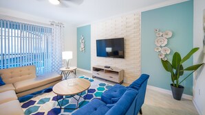 Un salon moderne comprenant un canapé, une table basse, un téléviseur et des éléments décoratifs.