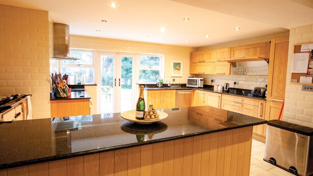 A modern kitchen with wooden cabinets, a large island, and a built-in microwave.