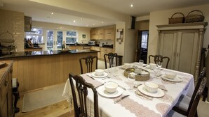 A modern kitchen with wooden cabinets, a central island, and a dining area set for six with a table set for a meal.