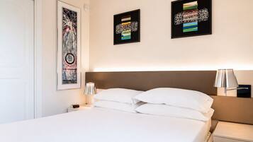 Une chambre d’hôtel avec un lit, une table de chevet, une lampe et deux œuvres d’art encadrées accrochées au mur.