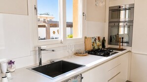 Una cucina moderna con lavello in acciaio inox, piano cottura a gas e forno.