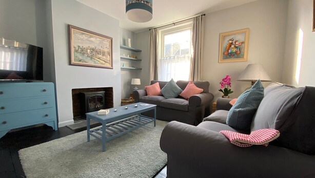 A living room with a fireplace, a sofa, a coffee table, and a television. - Just a stone’s throw from the beach (Walmer)