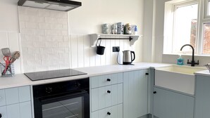 A modern kitchen with light blue cabinets, a black stove, and a window providing natural light. - Just a stone’s throw from the beach (Walmer)