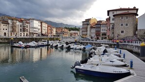 Un port esportiu amb vaixells amarrats, un pont de pedra i edificis amb balcons i finestres.