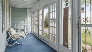A covered porch with white-framed glass doors, a blue carpet, and a white rocking chair. - Spacious Home- Centrally located near St. Paul  (Little Canada)