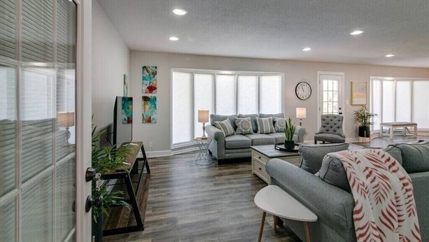 Un salon spacieux avec un canapé gris, une table basse et un coin repas équipé d’une banquette.