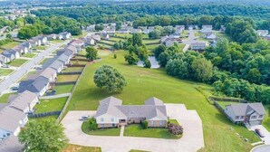 Un quartier résidentiel avec des maisons, des pelouses verdoyantes et une allée centrale.