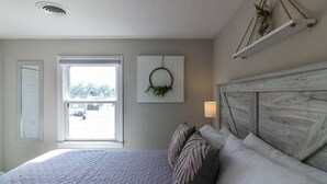 A bedroom with a bed, a window, a wall-mounted wreath, and a wooden headboard. - The Loft at Hilltop Acres - Clarksville, Tennessee (1335 Whitt Ln) (Clarksville)