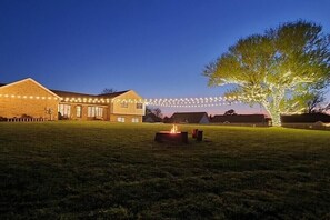 A large building with a grassy lawn, a fire pit, and string lights. - The Loft at Hilltop Acres - Clarksville, Tennessee (1335 Whitt Ln) (Clarksville)