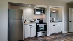 A modern kitchen with stainless steel appliances, white cabinetry, and a wooden floor. - The Loft at Hilltop Acres - Clarksville, Tennessee (1335 Whitt Ln) (Clarksville)