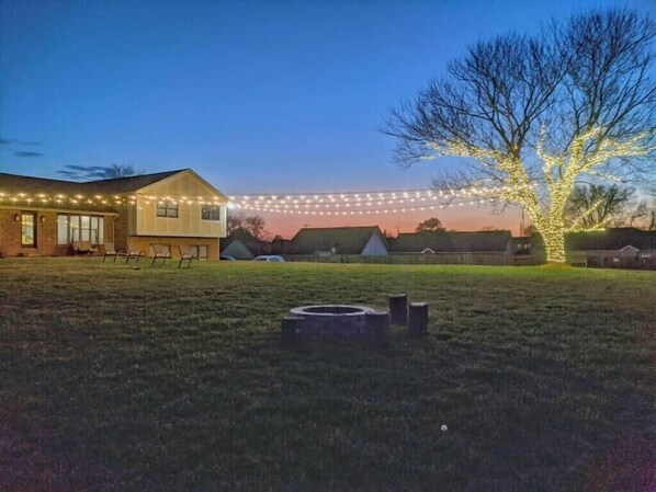 Una casa con jardín, luces colgantes y un árbol.