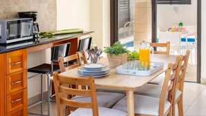 Une cuisine moderne équipée d’un four à micro-ondes, d’une machine à café et d’une table à manger pour quatre personnes.