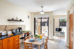 Une cuisine moderne avec un coin repas, un téléviseur et une vue sur l’extérieur.