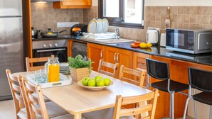 Une cuisine avec des meubles de rangement en bois, une cuisinière, un four à micro-ondes et une table à manger avec des chaises.
