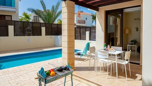Un espace aménagé au bord de la piscine, avec un barbecue, des chaises et une table.