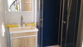 Une salle de bain avec une douche à parois incurvées, un lavabo avec un miroir au-dessus et des toilettes.