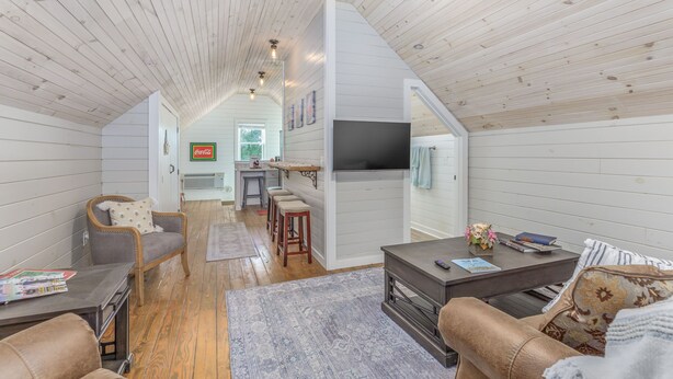 A cozy living room with a fireplace, wooden floors, and a TV mounted on the wall.