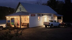 A G.H. Coetman Country Store with a white exterior, a small porch, and a white truck parked in front.