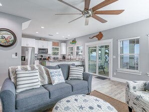 Relax in this stylish living area with a sofa, ceiling fan, and large window offering a view of the outdoors.