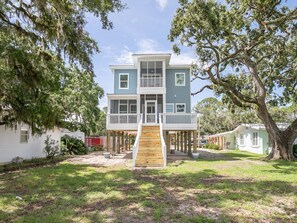 Stunning two-story house with a central staircase and covered porch, set amidst a serene lawn and mature trees.