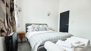 A neatly arranged bedroom with a bed, bedside table, and a bench with towels.