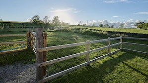 A wooden fence in a grassy field with a clear sky.