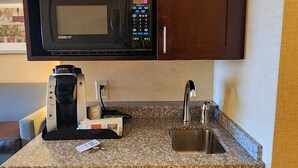 Une petite cuisine équipée d’un four à micro-ondes, d’une machine à café et d’un petit évier.