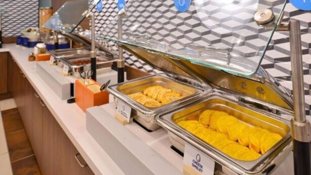 Un buffet proposant divers plats présentés dans des récipients en métal, avec une section intitulée « Omelette au fromage ».