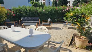 An outdoor seating area with a table and chairs, surrounded by greenery and a building in the background. -  LOVELY APART 2 BEDROOMS FOR 5-GARDEN GARAGE NEAR BEACHES PORT AND CITY CENTER (Cassis)