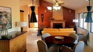 A living room with a fireplace, a sofa, and a dining table with chairs. - Villas San Ángel (Departamento) (Ajijic)