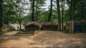 A rustic cabin with a chimney, a covered porch, and a small deck.