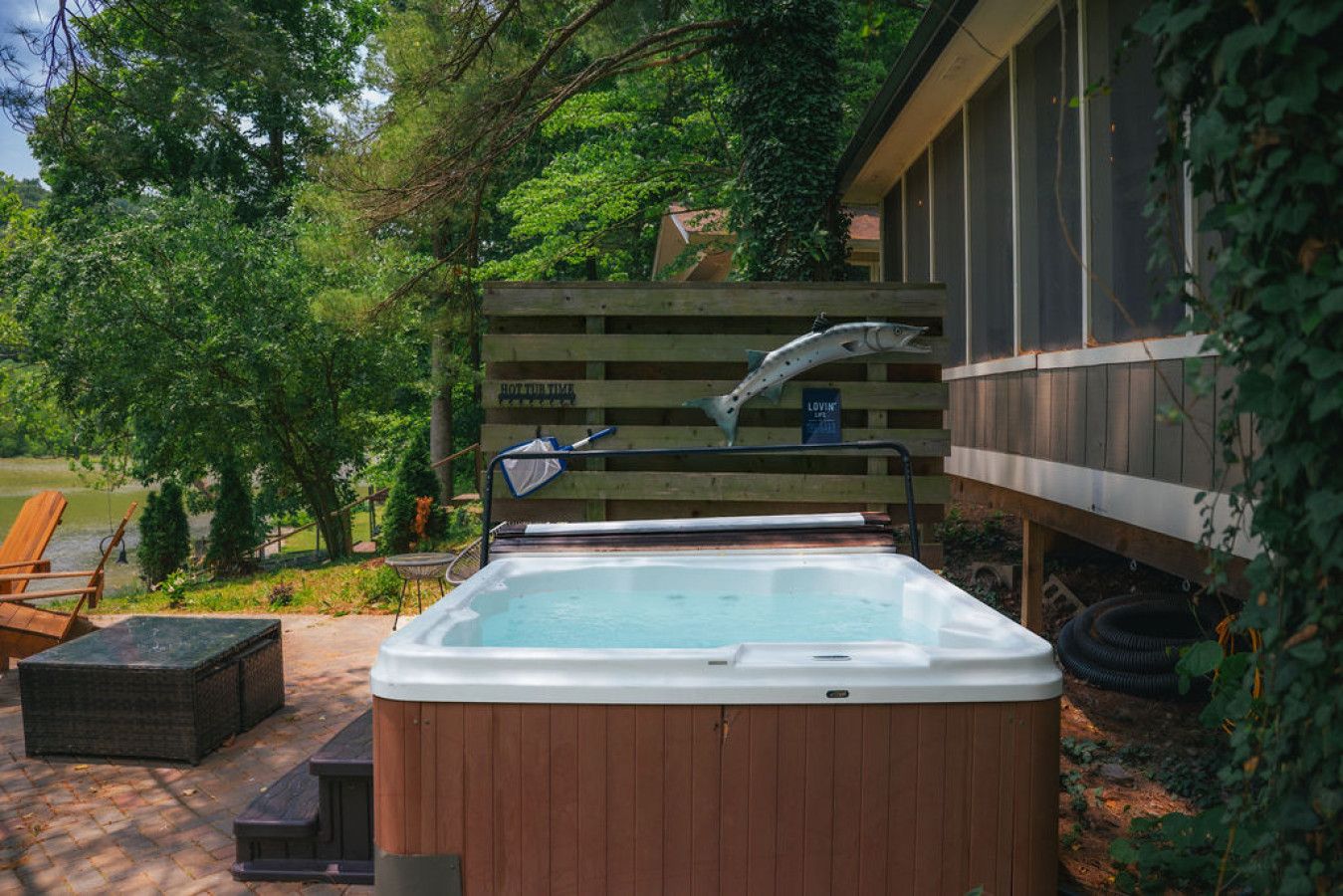 A hot tub with a wooden deck and a wooden fence in a backyard setting.