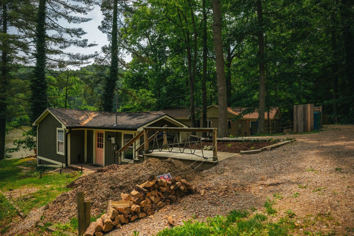 A rustic cabin with a porch, surrounded by a forest.