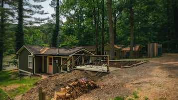 A rustic cabin with a porch, surrounded by a forest.