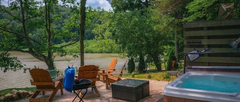 A patio area with outdoor seating, a hot tub, and a view of a river.