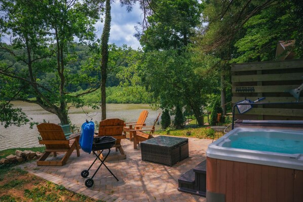 A patio area with outdoor seating, a hot tub, and a view of a river.