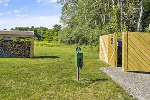 A rustic outdoor area with a wooden structure, a green mailbox, and a gravel path.