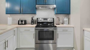 A kitchen with blue cabinets, a stainless steel stove, and white countertops.