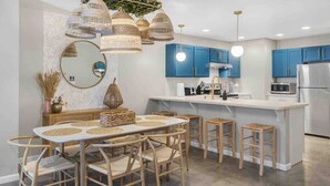 A modern kitchen with blue cabinets, a white island, and a dining area with a round table and chairs.