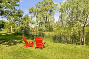 A grassy area with two red Adirondack chairs and a picnic table.