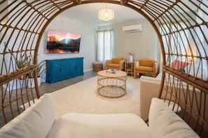A living room with a TV, two sofas, a coffee table, and a wicker arch.