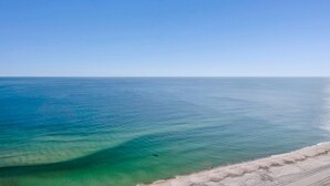 A beach with clear blue water and a sandy shore. - The Oasis 2105 | Spacious, Lazy River, Poolside Grill, New Splash Pad, Pool with Slide! (Orange Beach)